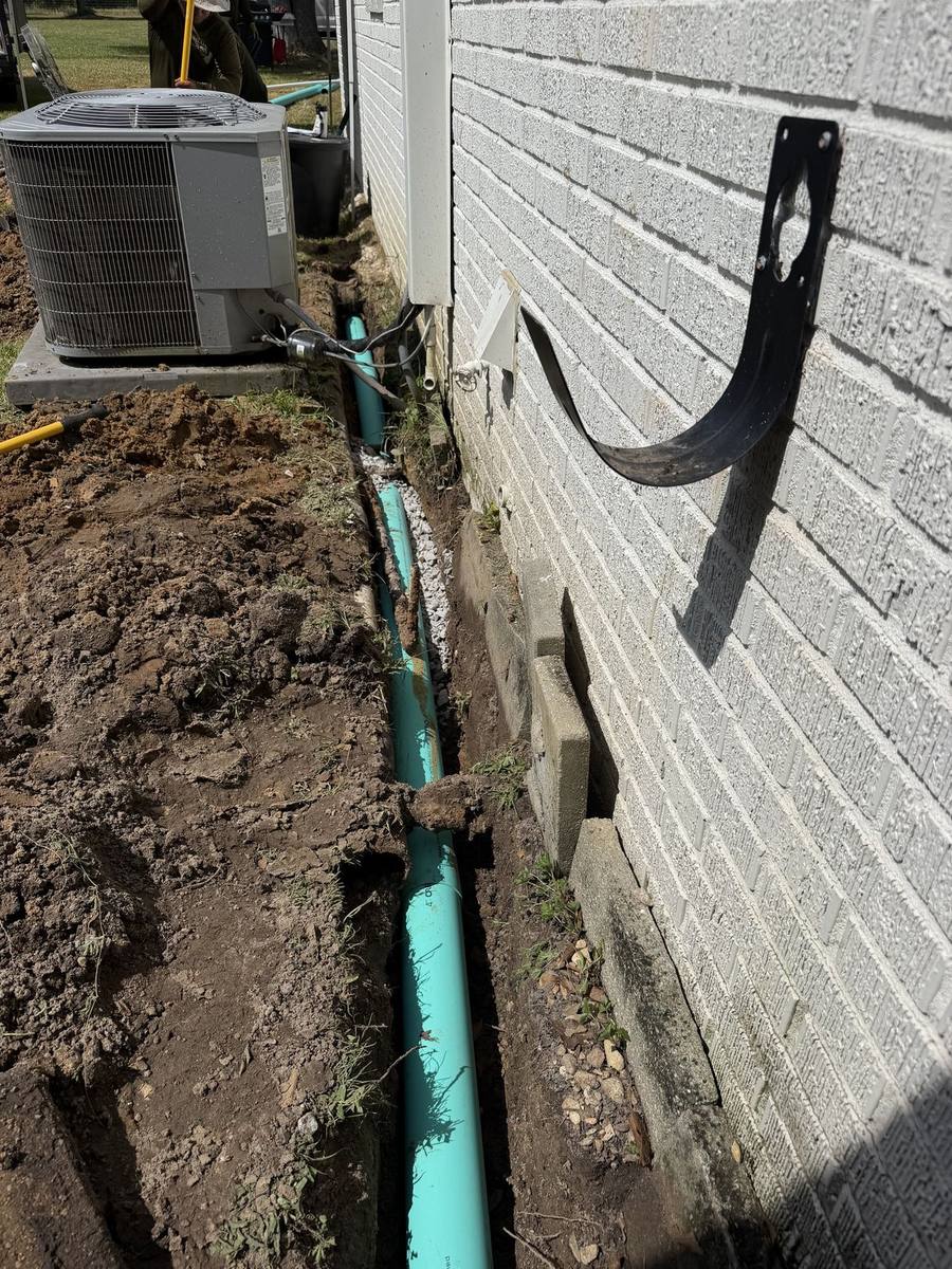 Drainage line routed along a home foundation and around the air conditioning unit