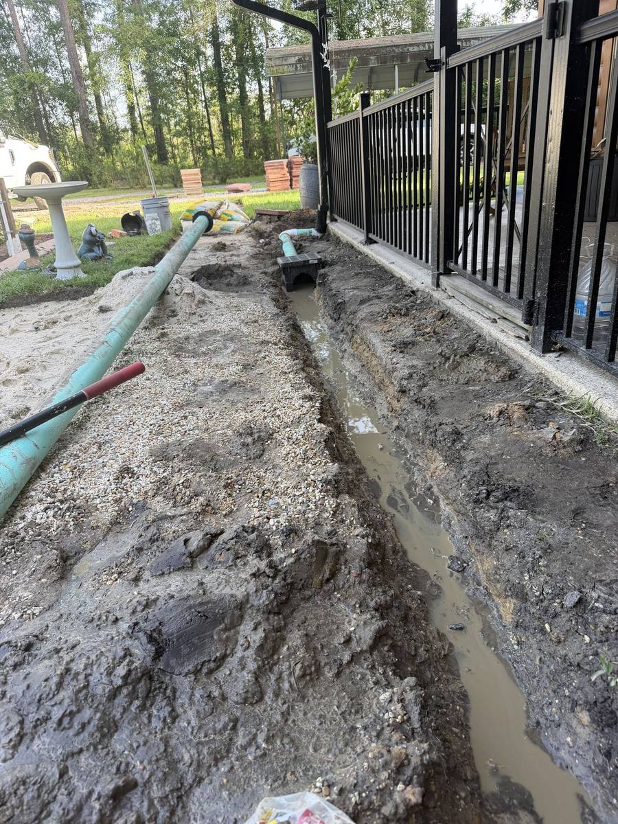 Solid drain pipe laid in a backyard trench running toward the property line