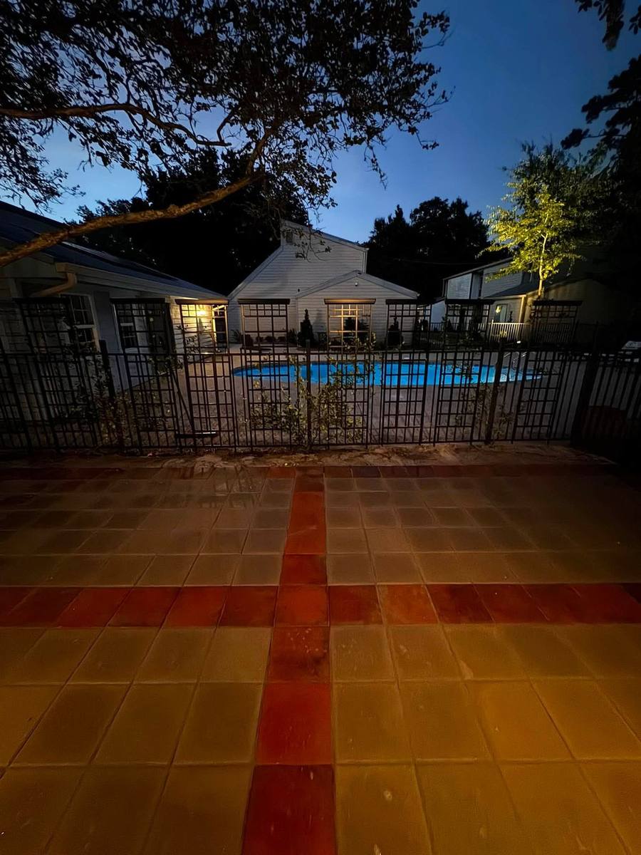 Paver pool patio with a red accent band photographed at dusk